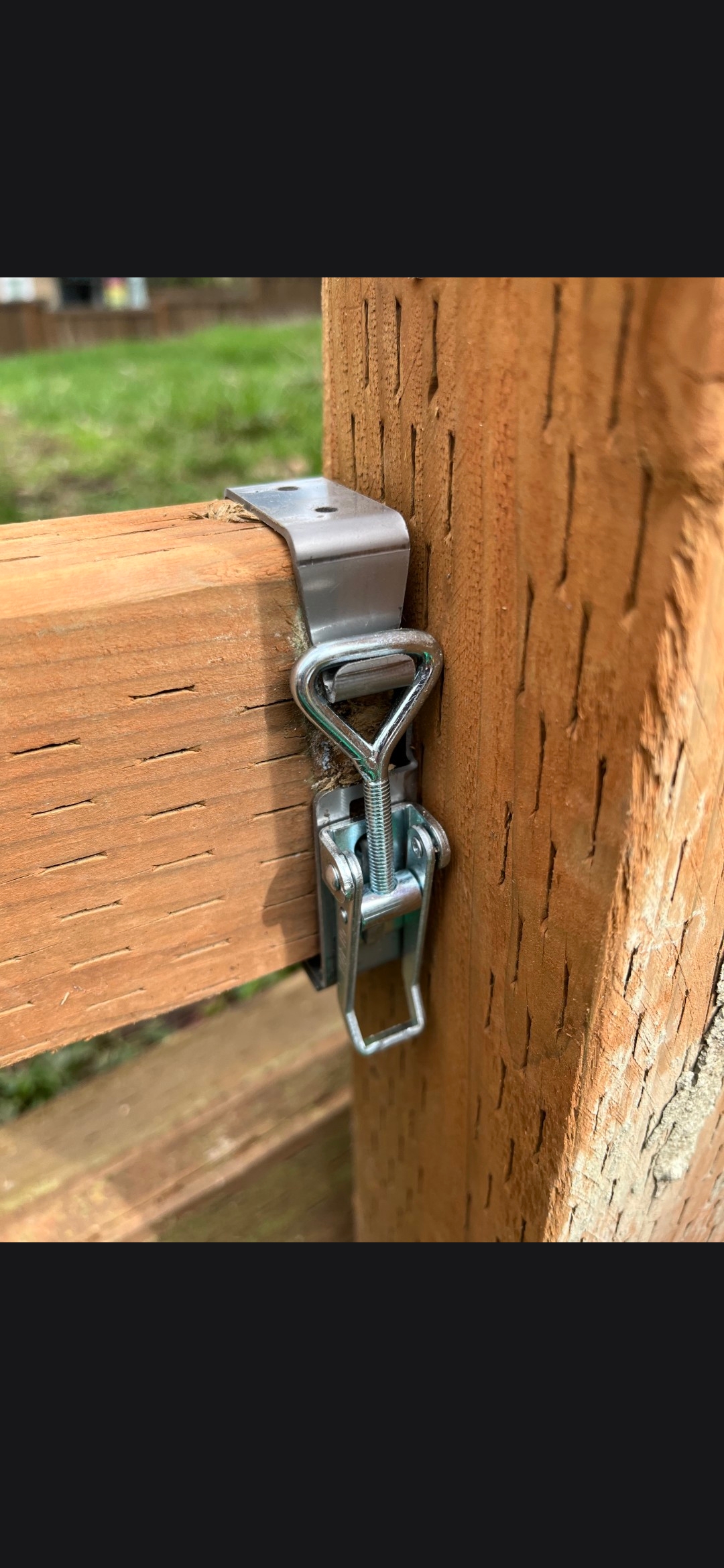 BITE BRACKET quick-release latch mounted on a wooden fence post and rail